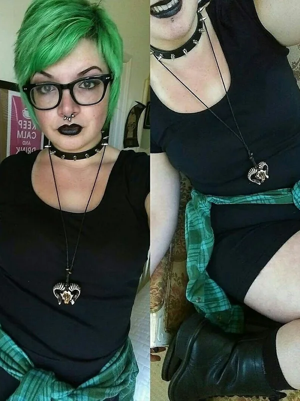 Personne aux cheveux verts, lunettes noires, maquillage sombre, vêtue de noir avec collier à clous et pendentif, écharpe verte, bottines